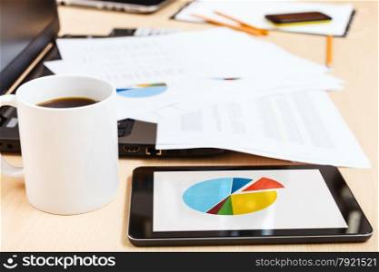business workflow - mug of coffee and tablet pc with chart on office table