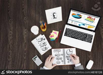 Business workplace with business stuff . Top view of business workplace and businessman hands writing in notepad