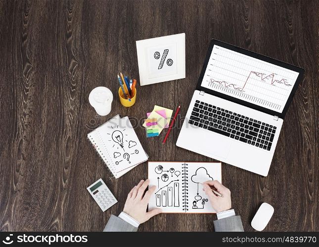 Business workplace with business stuff . Top view of business workplace and businessman hands writing in notepad