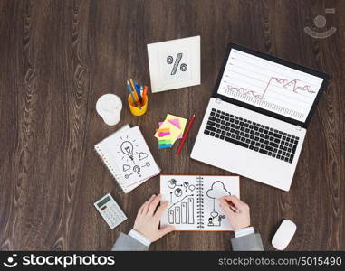 Business workplace with business stuff . Top view of business workplace and businessman hands writing in notepad