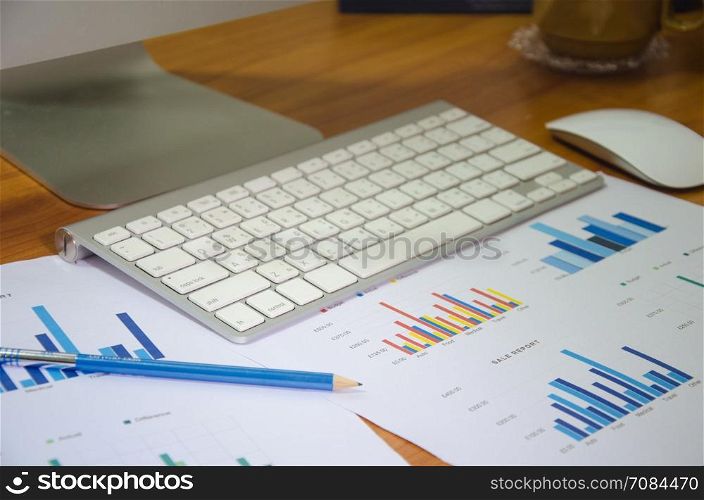 Business workplace with keyboard mouse and papers with graphs and diagrams