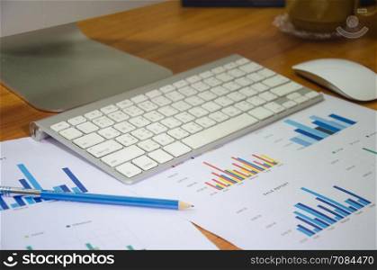 Business workplace with keyboard mouse and papers with graphs and diagrams