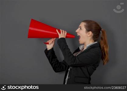 Business young woman speaking to a megaphone, over a grey background