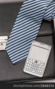 Businessman accessories tie and phone over leather briefcase