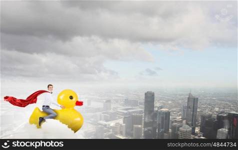 Businessman acting like child. Young happy businessman riding yellow rubber duck