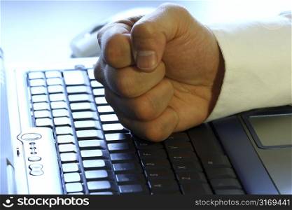 Businessman&acute;s fist on laptop, showing anger, excitement