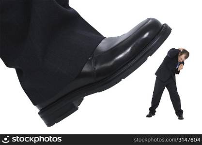 Businessman&acute;s foot stepping on tiny businessman. Metaphor for &acute;Crushing the Competition&acute; &acute;Squashing the Little Guy&acute; or for at work stress or power.