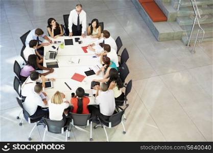 Businessman Addressing Meeting Around Boardroom Table