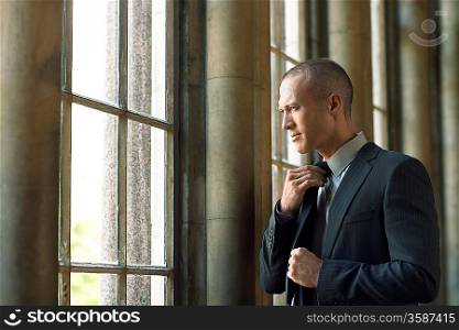 Businessman Adjusting Tie by window