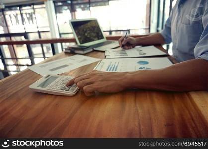 Businessman analyzing investment charts and pressing calculator buttons over documents. Accounting Concept.