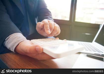 Businessman analyzing investment charts and pressing calculator buttons over documents. Accounting Concept.
