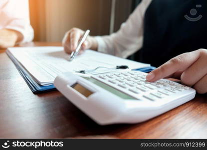 Businessman analyzing investment charts and pressing calculator buttons over documents. Accounting Concept