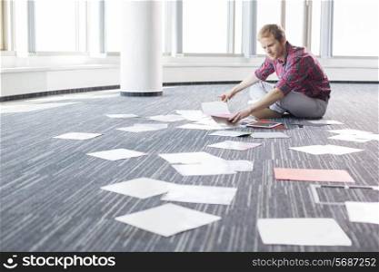 Businessman analyzing photographs while sitting on floor at creative office