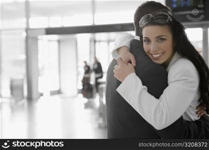 Businessman and a businesswoman embracing each other at an airport
