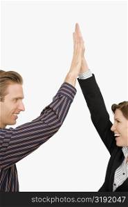 Businessman and a businesswoman giving high-five and smiling
