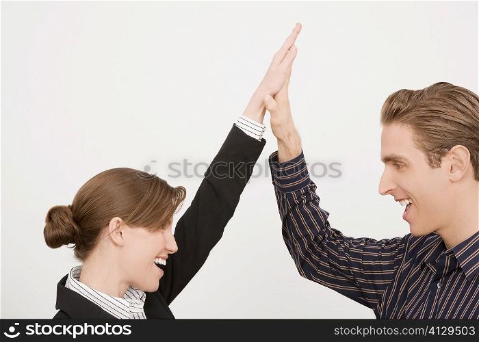 Businessman and a businesswoman giving high-five and smiling