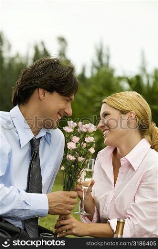 Businessman and a businesswoman holding a bunch of flowers looking at each other