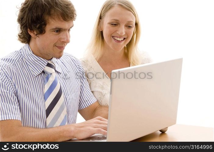 Businessman and a businesswoman looking at a laptop and smiling