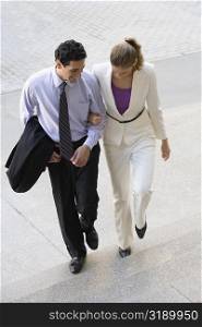 Businessman and a businesswoman moving up on steps with their arm in arm