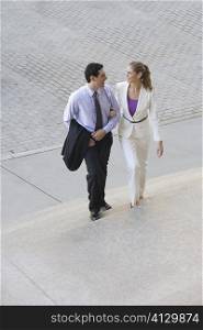Businessman and a businesswoman moving up on steps with their arm in arm