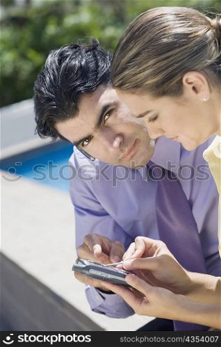 Businessman and a businesswoman operating a mobile phone