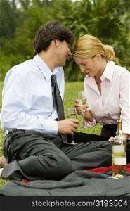 Businessman and a businesswoman sitting in the park holding champagne flutes