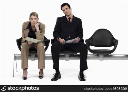 Businessman and a businesswoman sitting on a bench