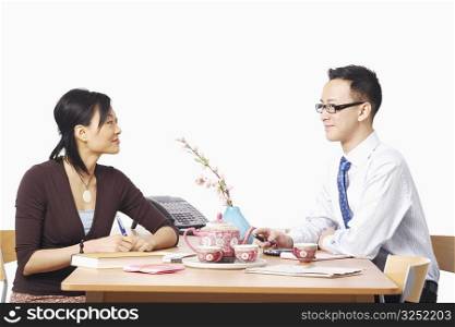 Businessman and a businesswoman sitting on chairs looking at each other