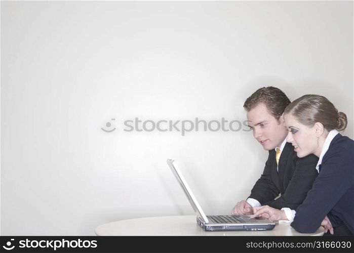 Businessman and a Businesswoman sitting together and using a laptop to get their work done in their office