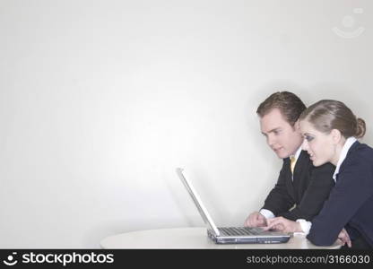 Businessman and a Businesswoman sitting together and using a laptop to get their work done in their office