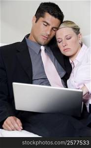 Businessman and a businesswoman sleeping in front of a laptop