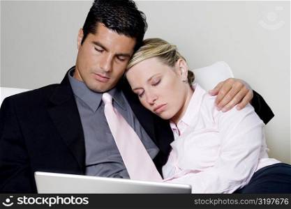 Businessman and a businesswoman sleeping in front of a laptop