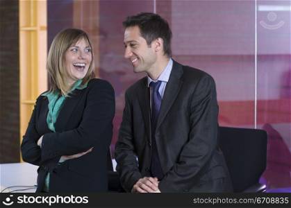 Businessman and a businesswoman smiling in an office