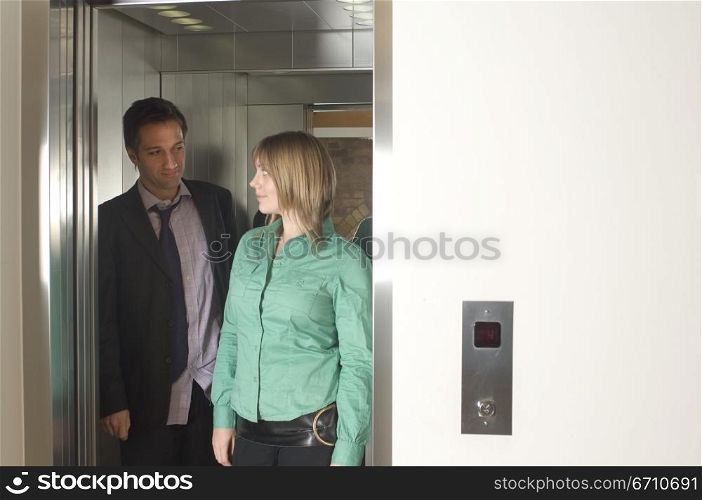 Businessman and a businesswoman standing in an elevator