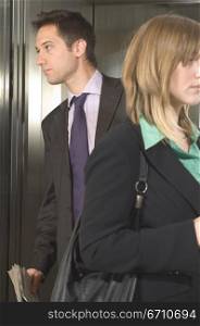 Businessman and a businesswoman standing in an elevator