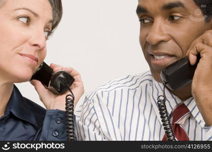 Businessman and a businesswoman talking on landline phones