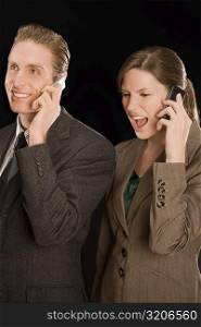 Businessman and a businesswoman talking on mobile phones