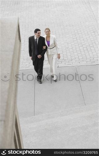Businessman and a businesswoman walking with their arm in arm