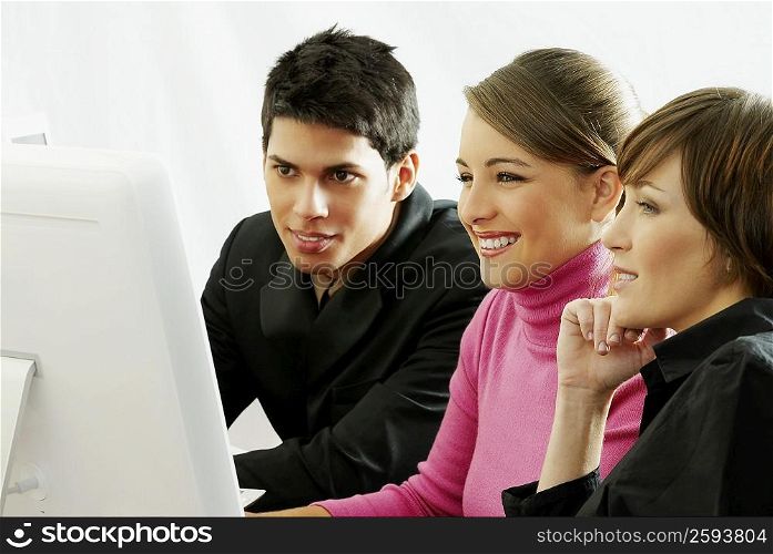 Businessman and a businesswoman with a teenage girl sitting in front of a computer monitor