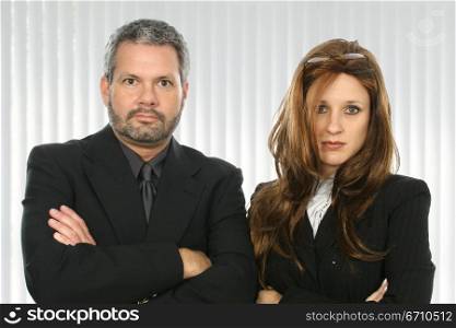 Businessman and a businesswoman with their arms crossed