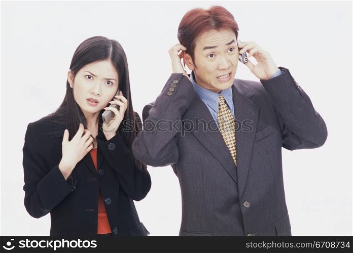 Businessman and a young businesswoman talking on mobile phones