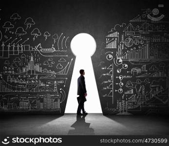 Businessman and business plan. Silhouette of businessman against black wall with key hole
