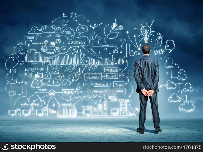 Businessman and business sketch. Back view image of young businessman standing against business sketch