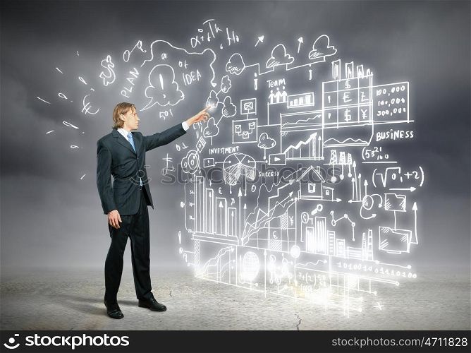 Businessman and business sketch. Image of young businessman standing against business sketch
