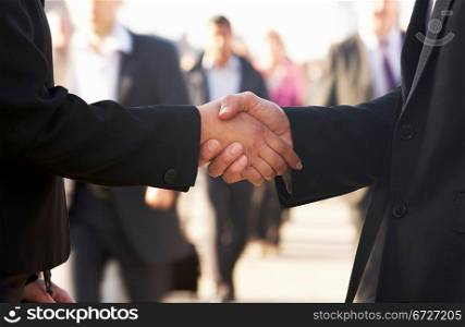 Businessman and business woman shaking hands in street