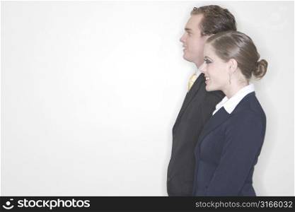 Businessman and Business woman standing together with a profile side view looking away