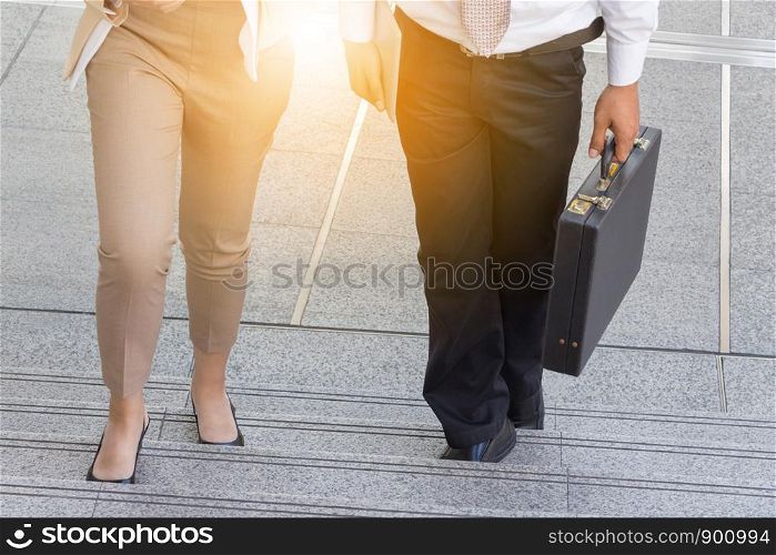Businessman and Business woman walking up stairs with bags to office.