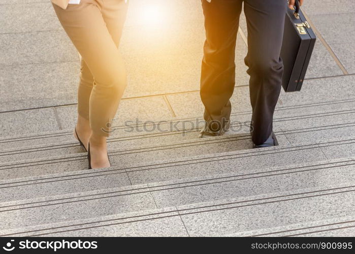 Businessman and Business woman walking up stairs with bags to office.