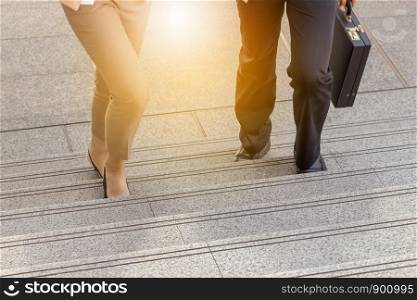 Businessman and Business woman walking up stairs with bags to office.