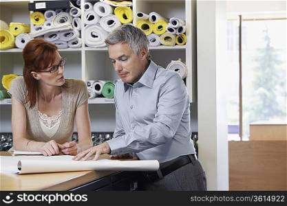 Businessman and Businesswoman Discussing Blueprint